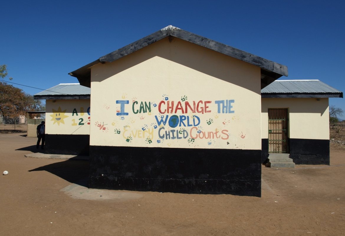 A school building with a mural reading I can change the world
